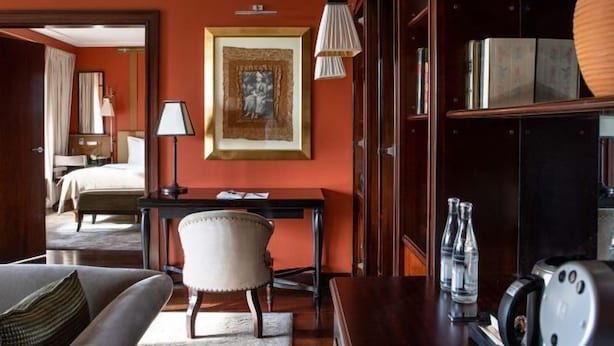 A hotel room with a bed, a desk, a chair, a bookshelf, and a framed picture on the wall. - La Réserve Genève Hotel & Spa (Geneva)