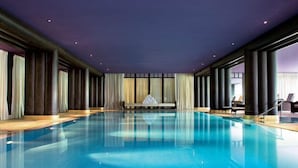 A large indoor swimming pool with a central bench, surrounded by tall columns and large windows. - La Réserve Genève Hotel & Spa (Geneva)