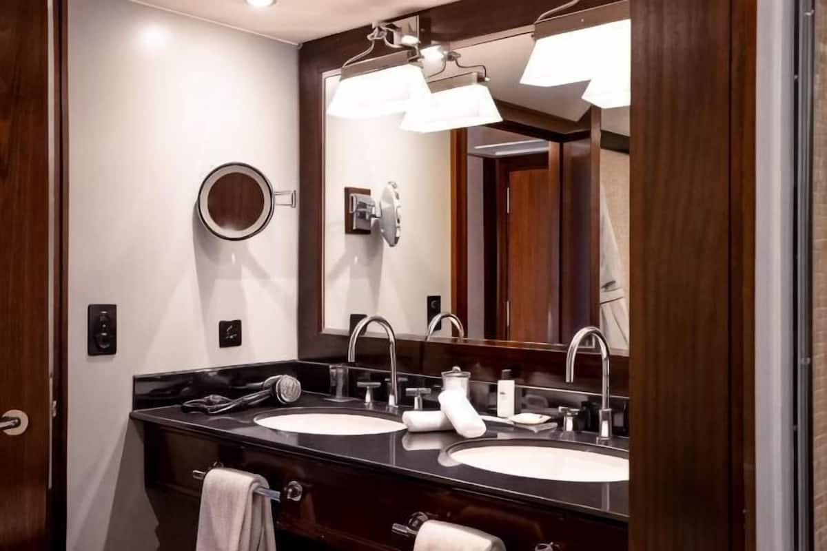 Un baño con dos lavamanos, un espejo grande y un perchero para toallas.