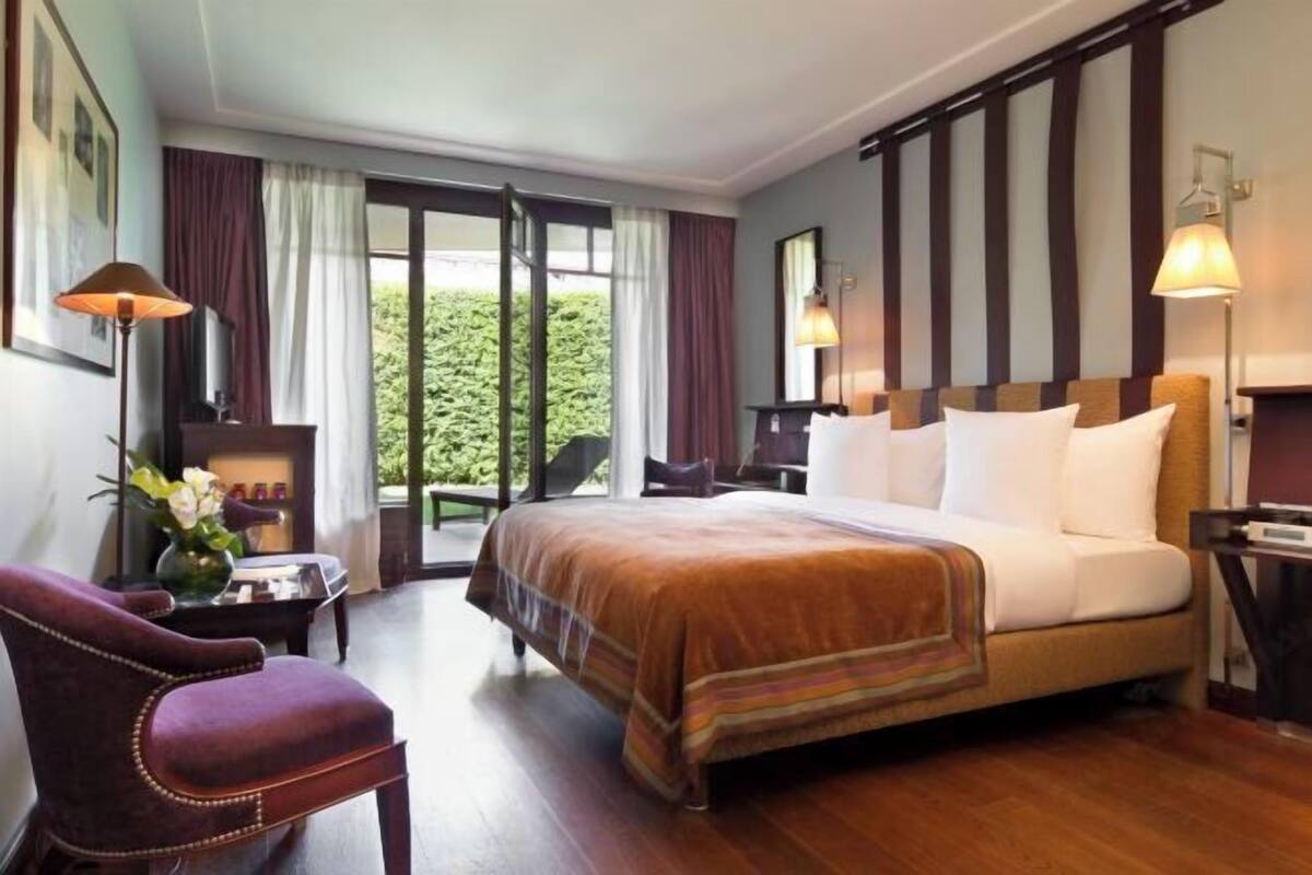Habitación de hotel con cama, una silla, un escritorio y vistas a zonas verdes.