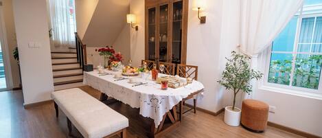 A dining area with a wooden table set for four, a bench, and a potted plant.
