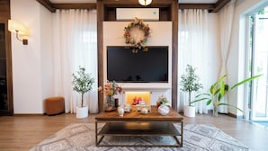 Een woonkamer met een open haard, een televisie en een salontafel met decoratieve objecten.