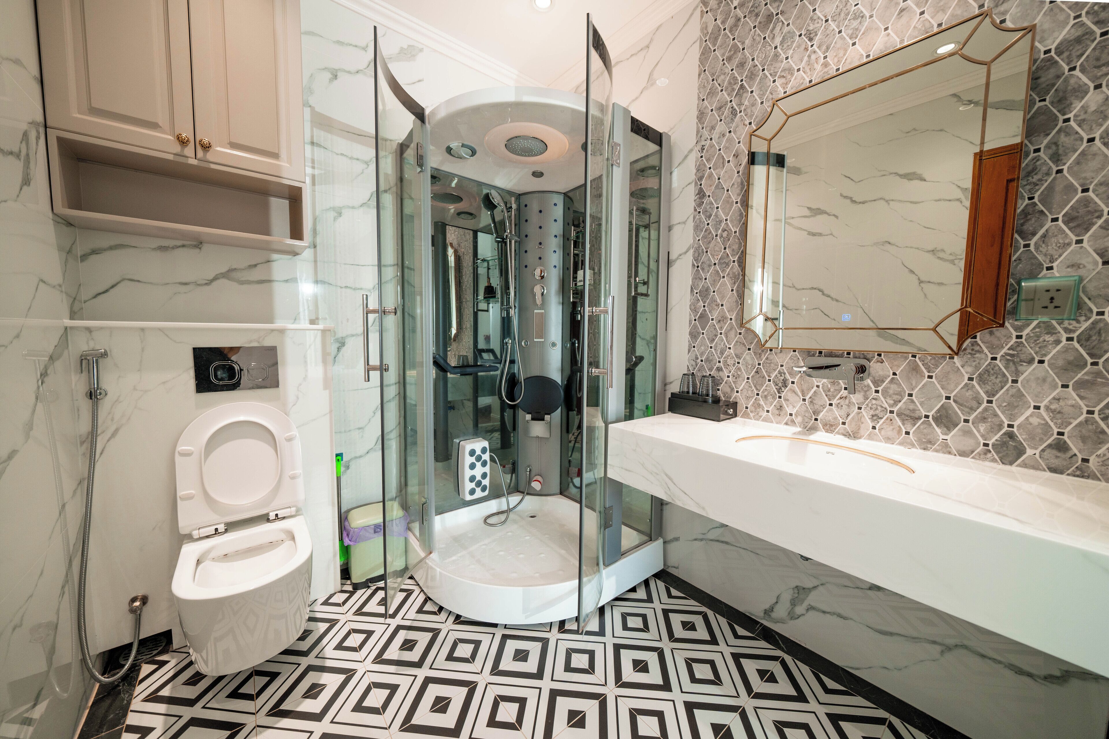 A modern bathroom with a glass-enclosed shower, a white toilet, a marble-patterned floor, and a large mirror.