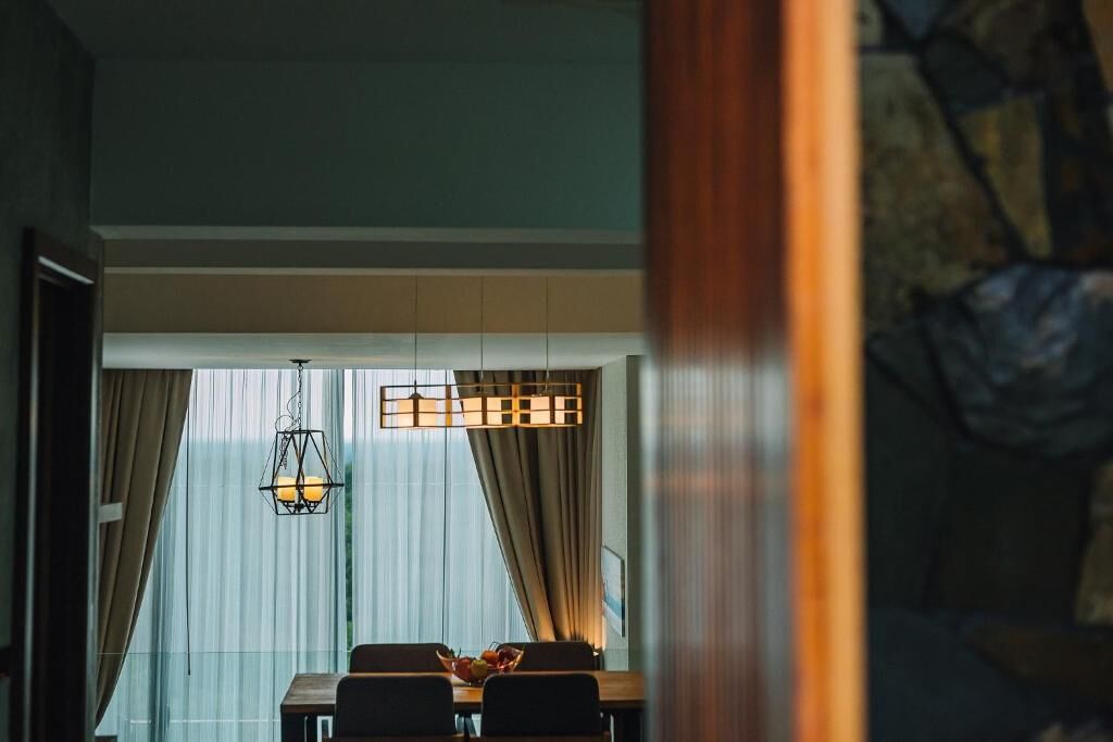A dining area with a table, chairs, and a hanging light fixture.