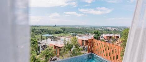A rooftop infinity pool with a view of a cityscape and greenery.