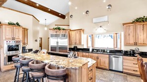 A spacious kitchen with wooden cabinets, stainless steel appliances, and a large island with bar stools.
