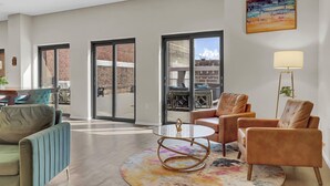A spacious living area with a large window, a round coffee table, leather armchairs, and a modern lamp. - Chic 1-bed loft in Playhouse square, near Stadiums, Theater, Dining, Pets OK (Cleveland)