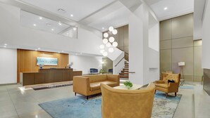 A modern lobby with a reception desk, sofas, a staircase, and a decorative light fixture. - Chic 1-bed loft in Playhouse square, near Stadiums, Theater, Dining, Pets OK (Cleveland)