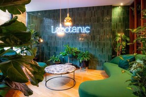 Un interior moderno con un letrero de neón, asientos verdes y plantas en macetas.