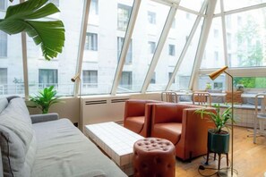 A modern living room with a sofa, a coffee table, and a plant. - Mercure Paris Montparnasse Pasteur (Paris)