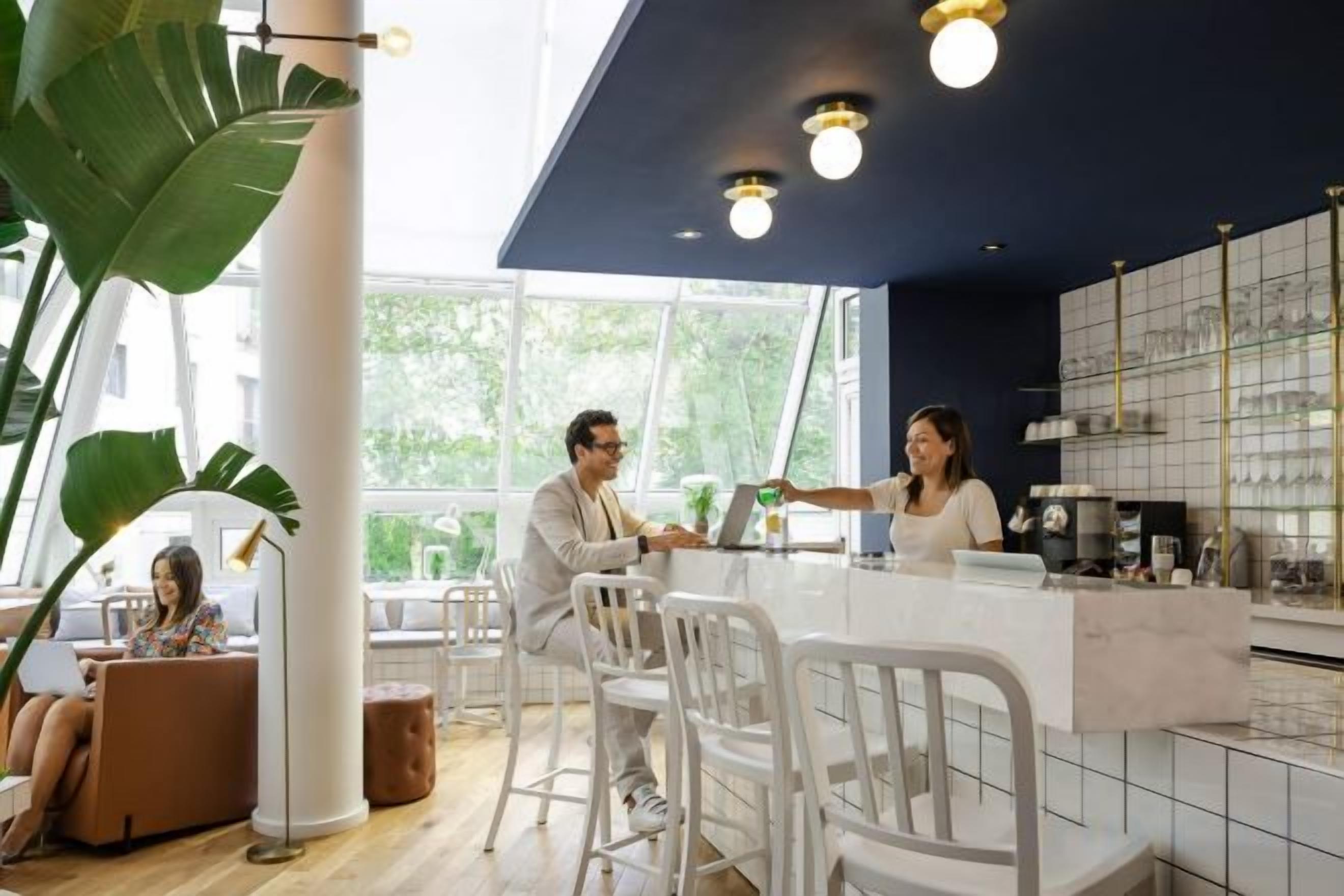 A modern bar area with a counter, seating, and large windows.