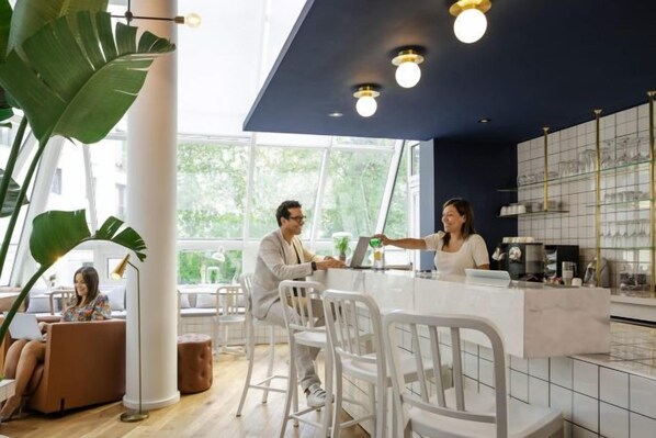 Un moderno espacio de bar con mostrador, asientos y ventanas amplias.