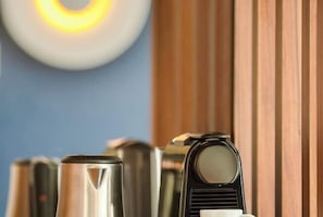 Une rangée d’objets cylindriques métalliques, qui pourraient être des machines à café, dans un décor moderne avec un mur bleu et un lambris en bois.