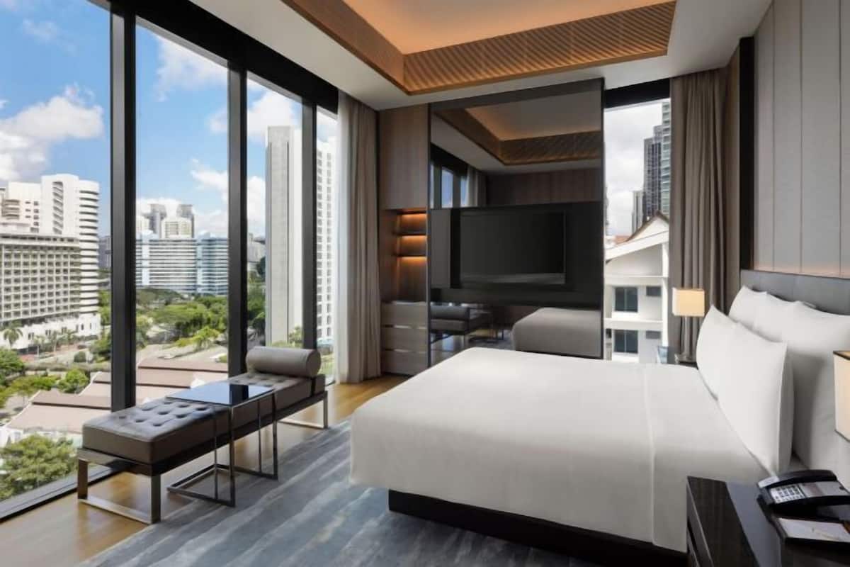 Una habitación de hotel moderna con una cama grande, un escritorio y televisión.