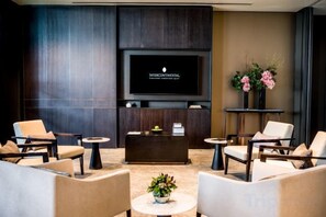 Un vestíbulo moderno con televisión de pantalla plana, sofás, una mesa de centro y plantas decorativas.