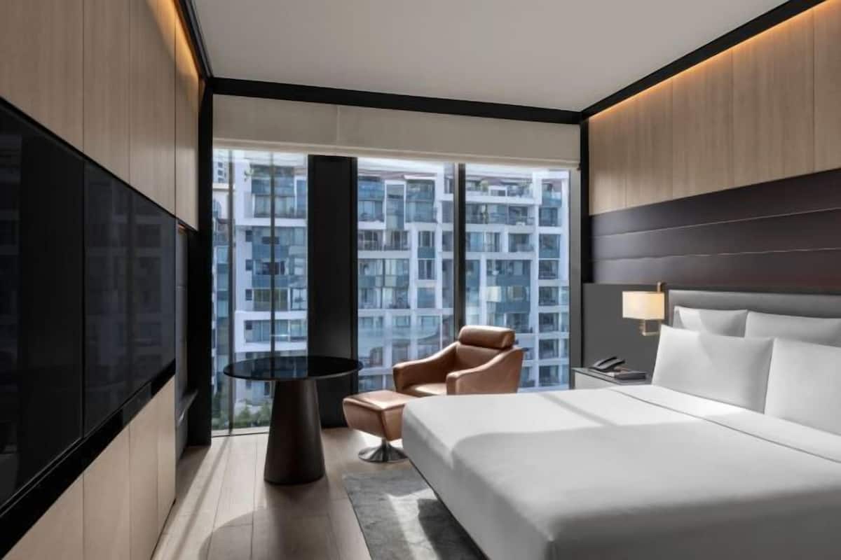 Una habitación de hotel moderna con una cama grande, una mesa redonda y una silla.