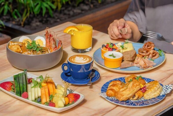Ein Frühstücksbuffet mit verschiedenen Speisen, einer Tasse Kaffee und einem Glas Orangensaft.