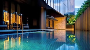 En modern inomhuspool med klart vatten, omgiven av en stilren byggnad med stora fönster och ett trästaket.