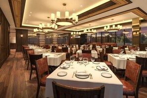Un restaurante con varias mesas dispuestas para comer, que cuenta con candelabros y un ambiente cálido.