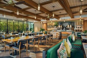 Un restaurante con techos altos, iluminación colgante y una zona de bar central.