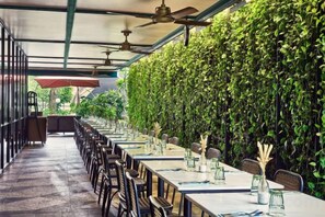 Un comedor interior con mesas, sillas, ventiladores de techo y una pared verde.