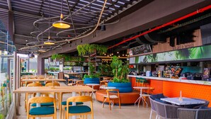 A modern restaurant with high ceilings, exposed ductwork, and a variety of seating options including bar stools, high tables, and booths. - Núcleo Sabana, San José, Apartment with A/C, 20 minutes from the Airport (San José)