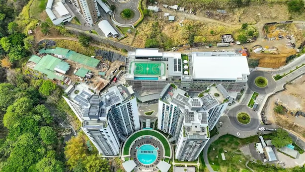 A high-rise building complex with multiple floors, a central courtyard with a swimming pool, and surrounding greenery. - Núcleo Sabana, San José, Apartment with A/C, 20 minutes from the Airport (San José)