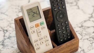 Two remote controls in a wooden holder on a marble surface.