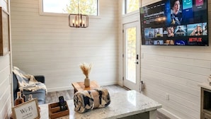 A modern living room with a flat-screen TV displaying a streaming service interface, a cozy seating area with a sofa and a coffee table, and a fireplace. - Turquoise Triangle Tiny Homes (Cottonwood)