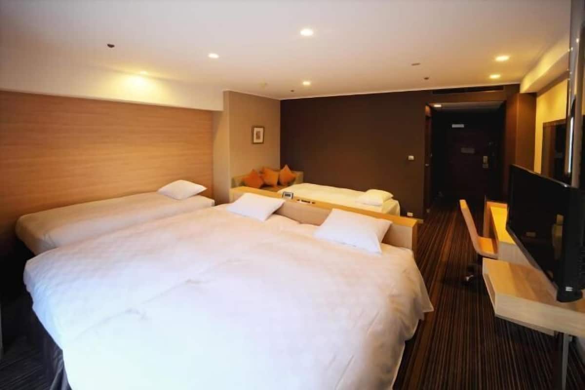 Habitación de hotel con dos camas, un escritorio y un televisor.