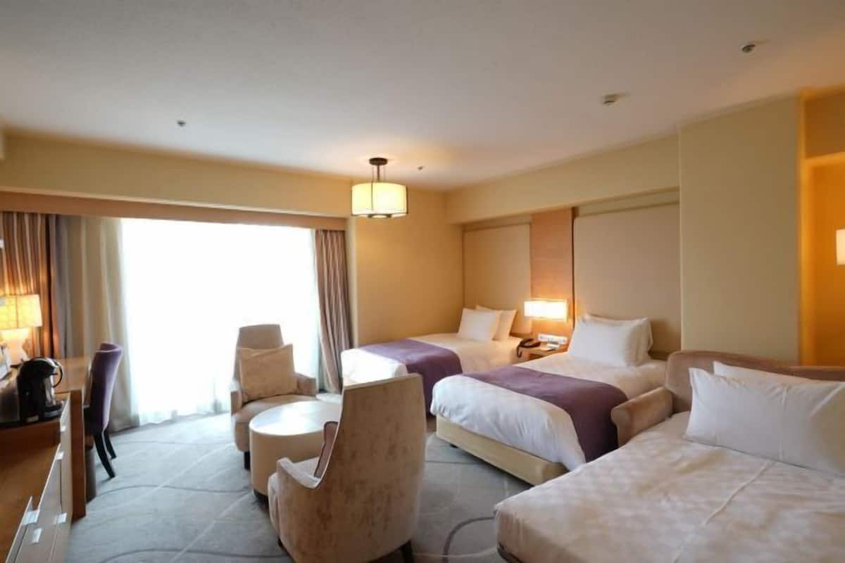 Una habitación de hotel con dos camas, un escritorio, una silla y una lámpara.