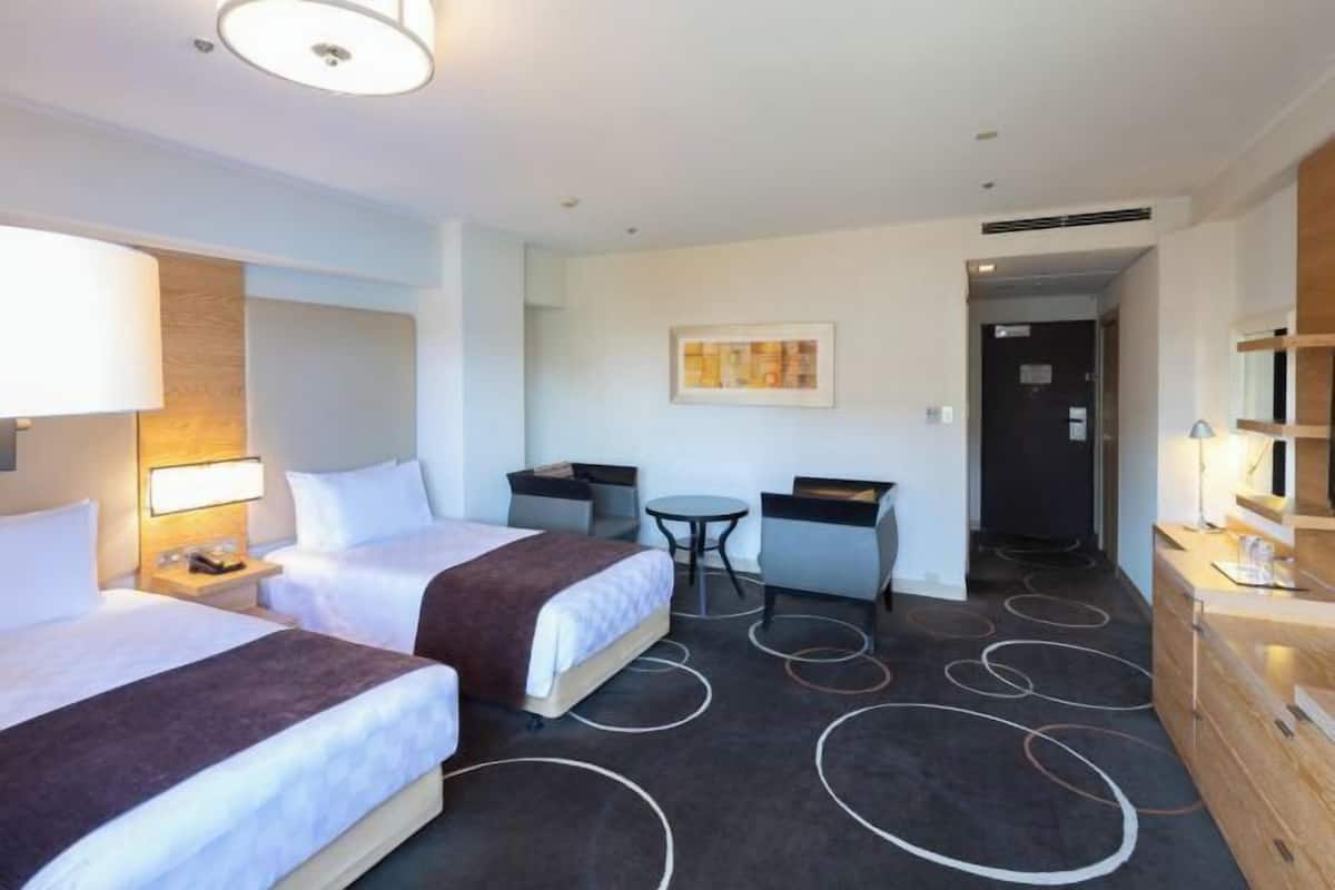 Una habitación de hotel con dos camas, un escritorio, una silla, una mesita y un espejo.