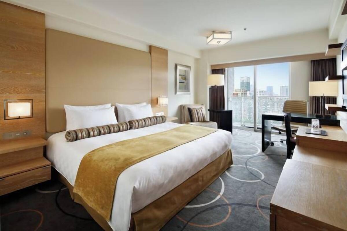 Habitación de hotel con una cama grande, un escritorio, una silla y vistas a la ciudad.