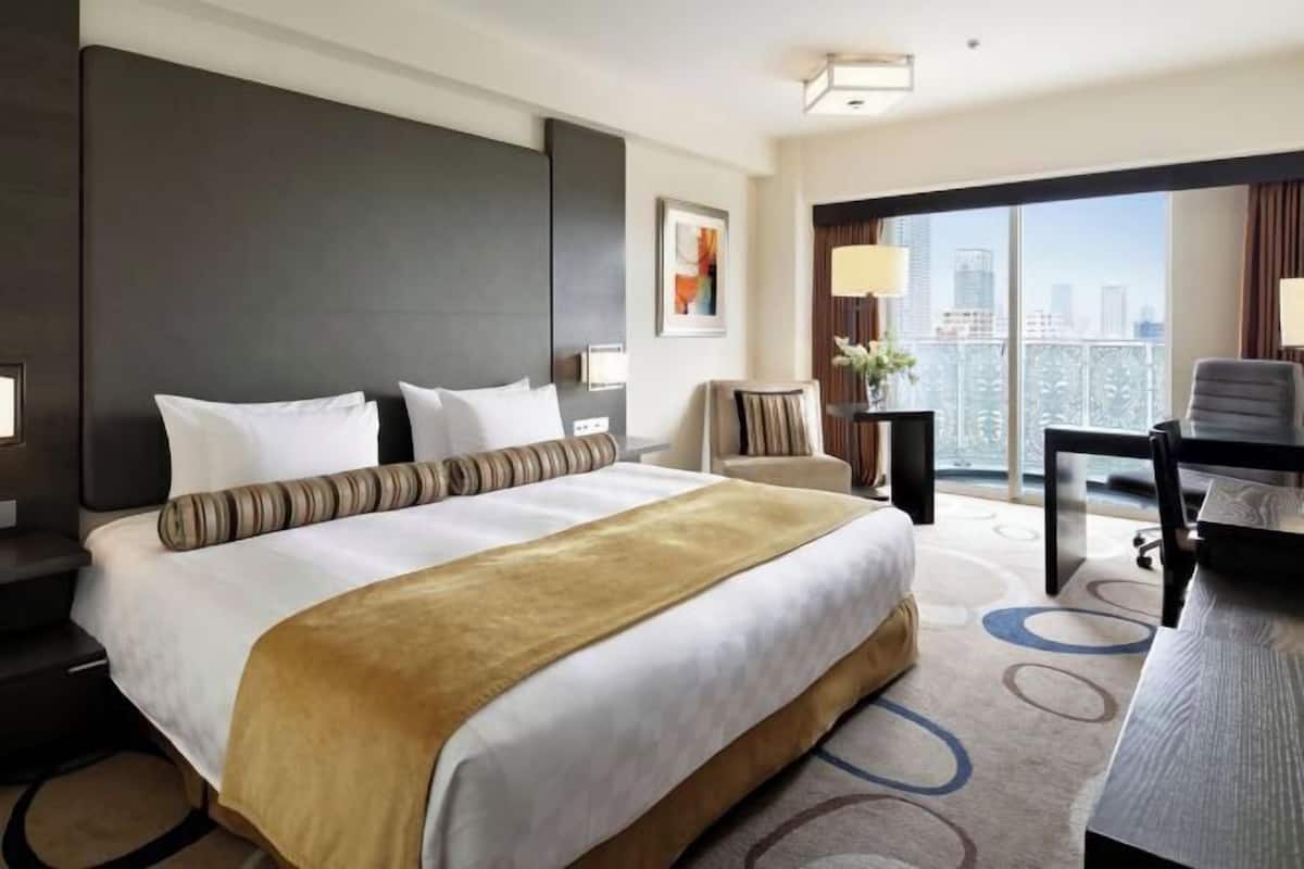 Una habitación de hotel con una cama grande, un escritorio, una silla y vistas a la ciudad.