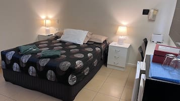 Une chambre d’hôtel comprenant un lit, des tables de chevet, un bureau, une chaise et un réfrigérateur.