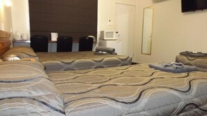 A hotel room with a large bed, a desk, a chair, a television, and a mirror. - THREE MOON MOTEL (Monto)