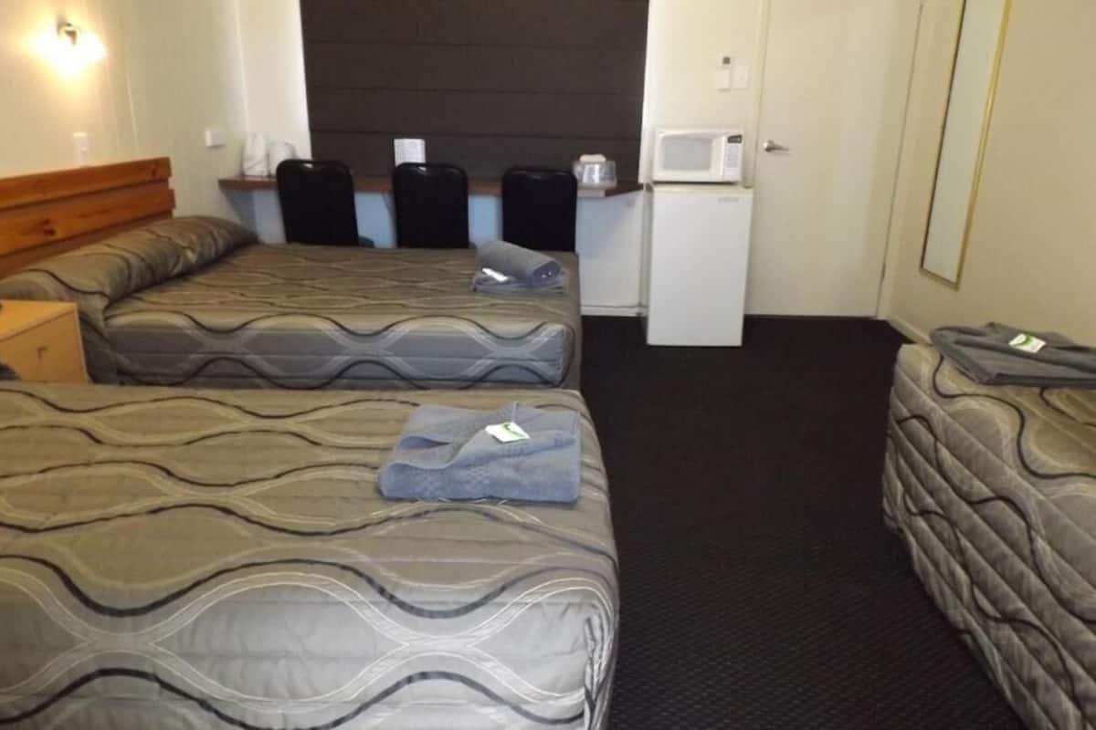 A hotel room with two beds, a small kitchenette, and a microwave.