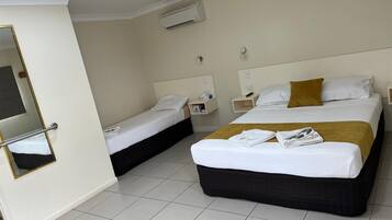 Ein Hotelzimmer mit zwei Betten, einem Spiegel, einem Nachttisch und einer Klimaanlage.