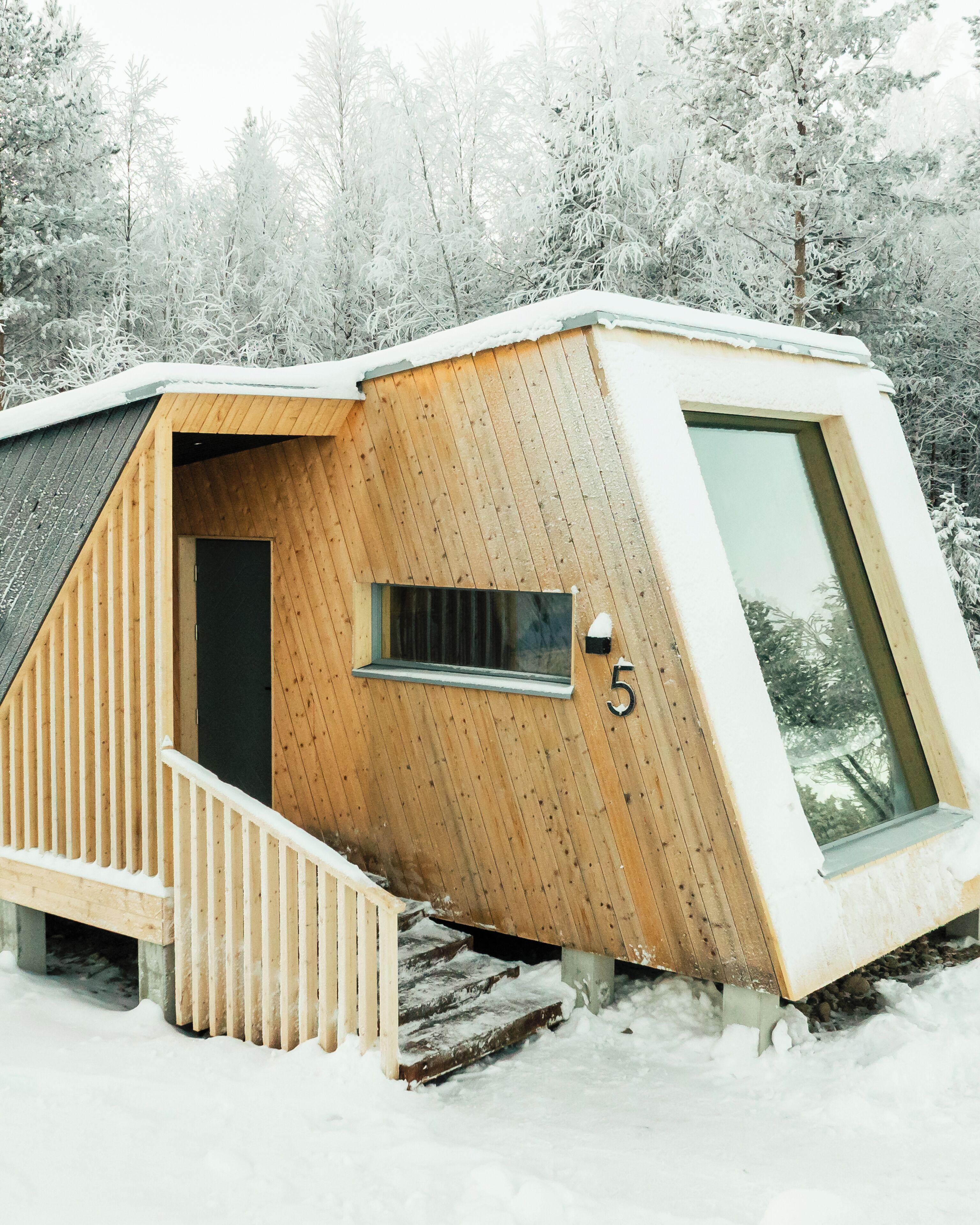Una cabaña de madera con techo inclinado, una ventana pequeña y el número 5 en el lateral.