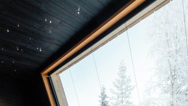 A room with a large window overlooking a snowy forest. - Lapland Glow Chalets (Rovaniemi)