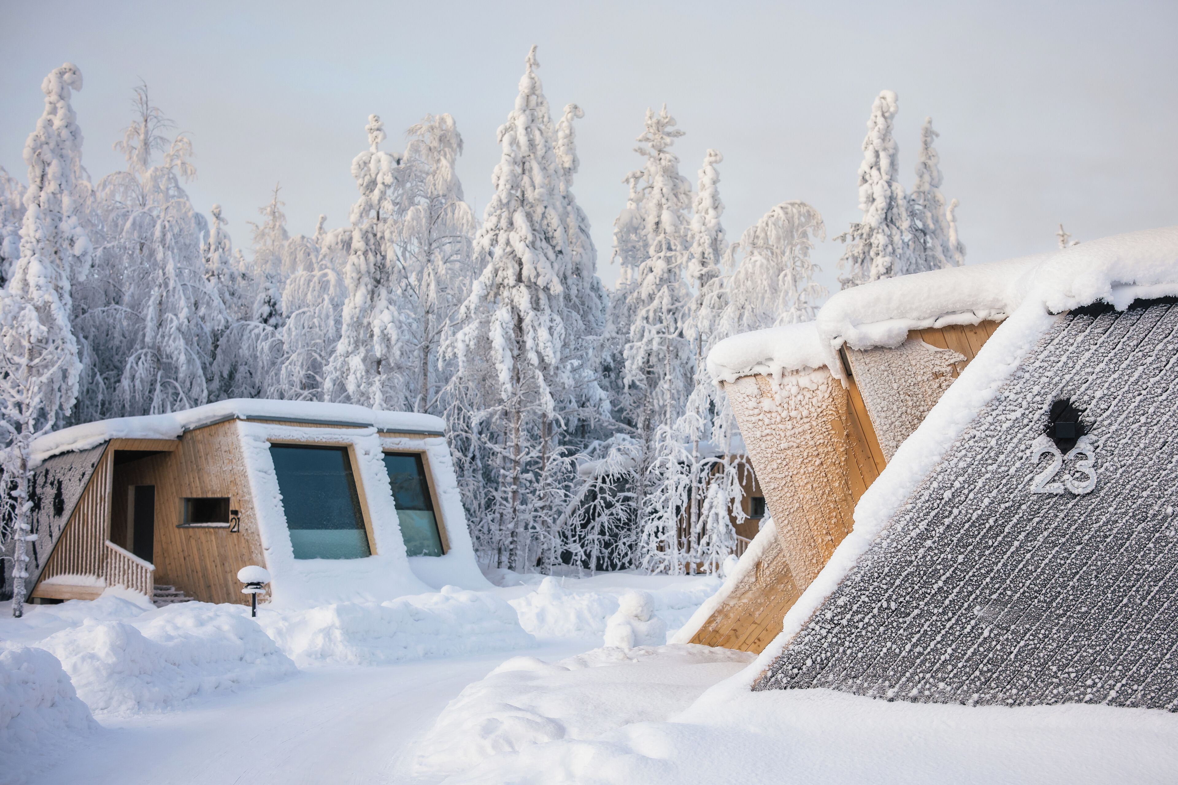Ein mit Schnee bedecktes Holzhaus mit einer kleinen Veranda und einem großen Fenster.