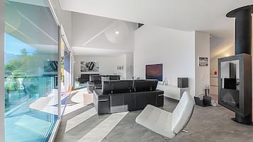 A modern living room with a black leather sofa, a white chair, and a fireplace.