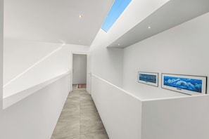 A modern, minimalist hallway with a skylight, white walls, and two framed pictures on the right. - Villa Mondacce With Jacuzzi & Lake Views (Minusio)