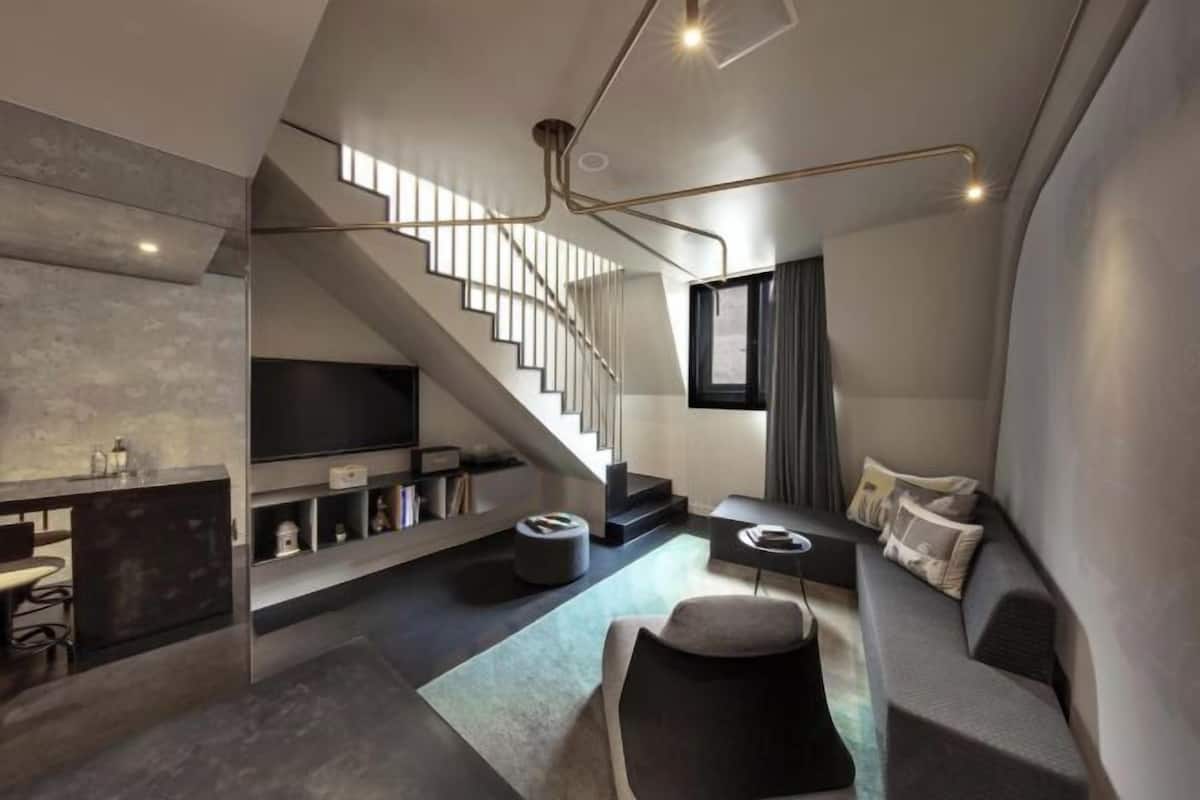 A modern interior with a staircase, a flat-screen TV, a sofa, and a dining area.