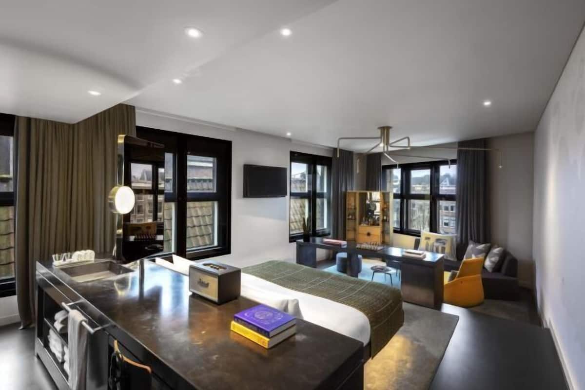 A modern hotel room with a bed, desk, and seating area.
