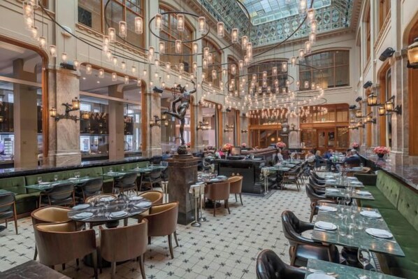 A spacious restaurant with high ceilings, chandeliers, and a central fountain. Tables are set for dining. - W Amsterdam (Amsterdam)