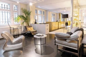 Un salon moderne avec un canapé, un fauteuil et une table basse. Il y a également un coin cuisine avec des placards et un téléviseur.