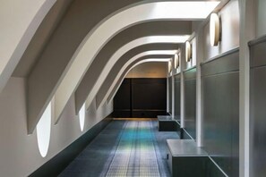 Ein Korridor mit einem gemusterten Teppich, einer gewölbten Decke und einer Tür am Ende.