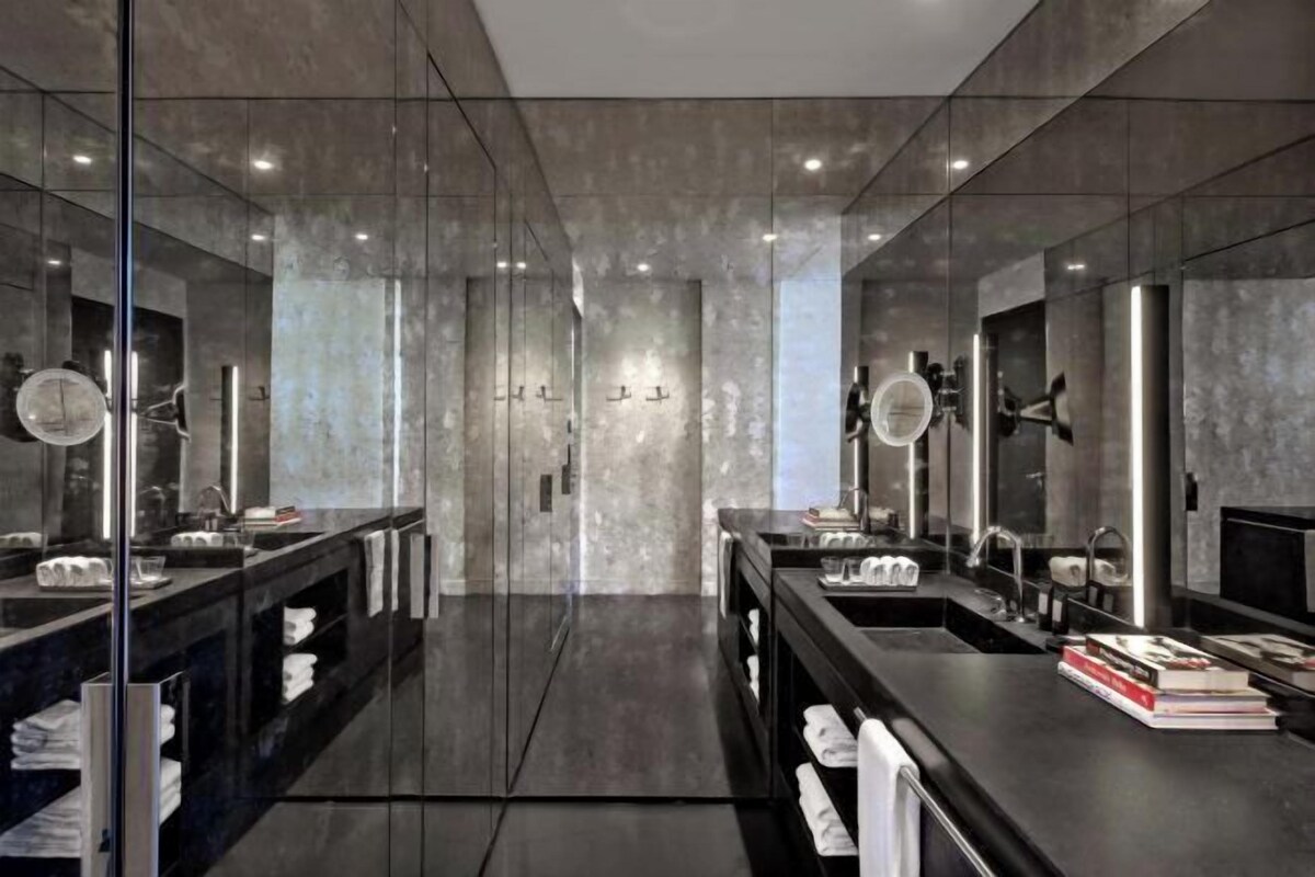 A modern bathroom with two sinks, large mirrors, and a glass partition.