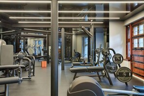 Une salle de sport équipée de matériel d’exercice, de miroirs et d’une grande fenêtre.